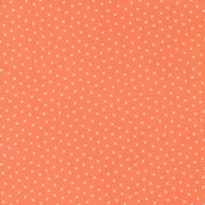 May include: Close-up of a coral-colored fabric with a repeating pattern of small white crosses. The fabric has a textured appearance, suggesting it may be cotton or a similar material. The design is evenly spaced across the surface.