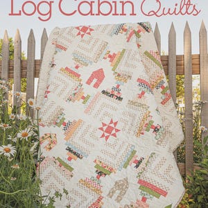 May include: A cream-colored quilt with a log cabin design, featuring red, green, and blue accents. The quilt is draped over a wooden fence, with the text "Creative Log Cabin Quilts" and "10 Fresh, New Designs" visible.