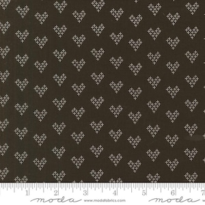 May include: Dark brown fabric with a repeating pattern of white cross-stitch hearts. The fabric has a ruler along the bottom edge with the word "moda" printed on it.