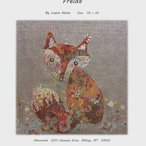 May include: A fabric art piece titled "Freida" by Laura Heine, featuring a fox design. The artwork is 35 x 35 inches and showcases a detailed patchwork fox in shades of orange, red, and brown, set against a textured gray background.