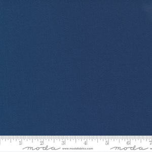May include: A close-up of a solid navy blue fabric with a subtle texture. The fabric is evenly lit, showing a consistent color and weave. A ruler is placed at the bottom, with measurements in inches. The fabric is from Moda Fabrics.
