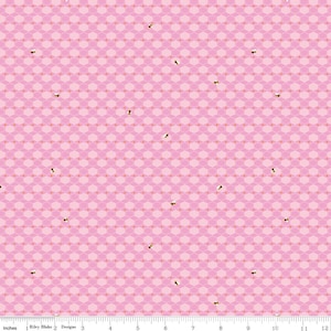 May include: Pink fabric with a geometric honeycomb pattern and scattered bee illustrations. The fabric has a repeating design of hexagons in varying shades of pink, with small, stylized bees. The bottom of the fabric has a ruler with inches.