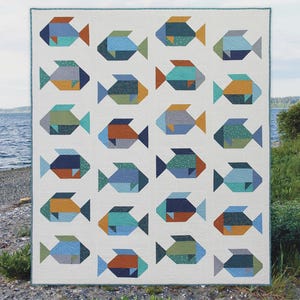 May include: A quilt featuring a repeating pattern of stylized fish in various shades of blue, green, and orange on a white background. The text "Fish" appears at the top, and "Cluck Cluck Sew A fat quarter quilt in 3 sizes" is at the bottom.
