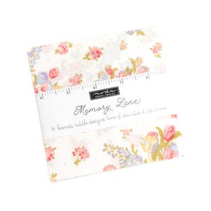 May include: A stack of fabric squares with a floral pattern in pink, purple, and yellow on a white background. The fabric is labeled "Memory Lane" by Moda Fabrics. A ruler is printed on the fabric.
