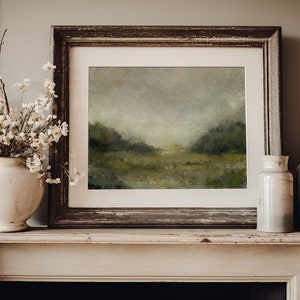 May include: A framed landscape painting of a misty green field with a wooden frame on a white mantelpiece with two ceramic vases.