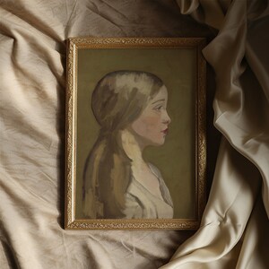 a portrait of a girl in neutral colours is in a gold gilded frame on beige silk