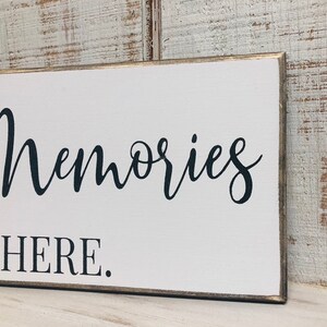 May include: White wooden sign with black text that reads "Memories Made Here."