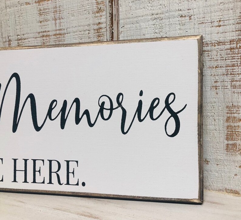 May include: White wooden sign with black text that reads "Memories Made Here."