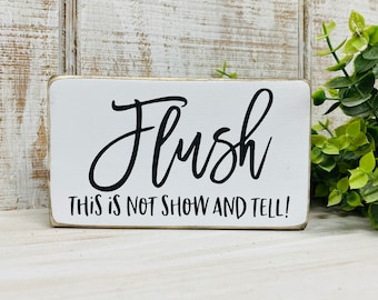 May include: White wooden sign with black text that reads "Flush This is not show and tell!"