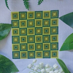 May include: A cross-stitch pattern with a repeating geometric design of squares in shades of green and yellow.