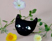 Schwarze Katzenbrosche. Textiler Katzenschmuck. Textiler schwarzer Katzenschmuck mit gemalten Augen und einer rosa herzförmigen Nase.
