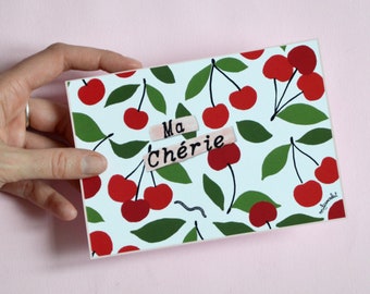 Carte Postale Ma chérie - Carte 14,8 cm X 10,5 cm illustrée de cerises rouges avec le message Ma chérie écrit au milieu .
