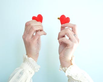 Hjärtformade hårspännen i röd sammet med guldfärgad bas.