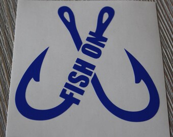 May include: A white square sticker with a blue design. Two crossed fishing hooks form an X, with the words "FISH ON" in blue across the center. The sticker is on a wood-grain surface.