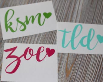 May include: Three white cards with names written in cursive and a small heart next to each name. The names are Zoe, ksm, and tld. The hearts are red, green, and blue.