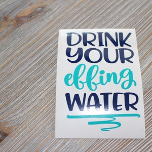 May include: White sticker with the text "Drink your effing water" in blue and turquoise lettering.