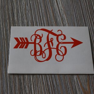 Op de afbeelding: Rode vinyl sticker met een monogram van de letters "B F G" in een cursief schrift, met een pijl die naar rechts wijst. De pijl en het monogram bevinden zich op een witte achtergrond.