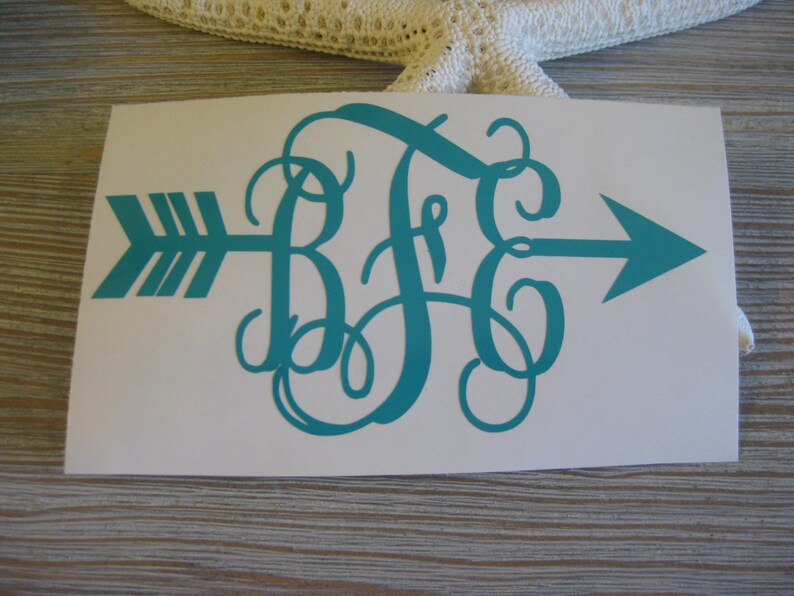 Op de afbeelding: Tealblauwe monogram sticker met de letters "B F C" in een cursief lettertype. Het monogram is gecentreerd op een witte achtergrond met een tealblauwe pijl die naar rechts wijst.