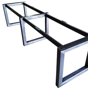 May include: A metal table base with a rectangular top and four legs. The base is made of black metal and has a simple, industrial design.