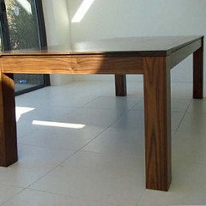 May include: A rectangular wooden dining table with a dark brown finish. The table has a simple design with four square legs and a flat top.