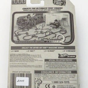 May include: A Hot Wheels Track System toy car packaging with a black and white image of a track set. The packaging features the text "Create the Ultimate Test Track!" and "Collect the entire Hot Rod Magazine Series!" The packaging also includes a special collector poster offer.