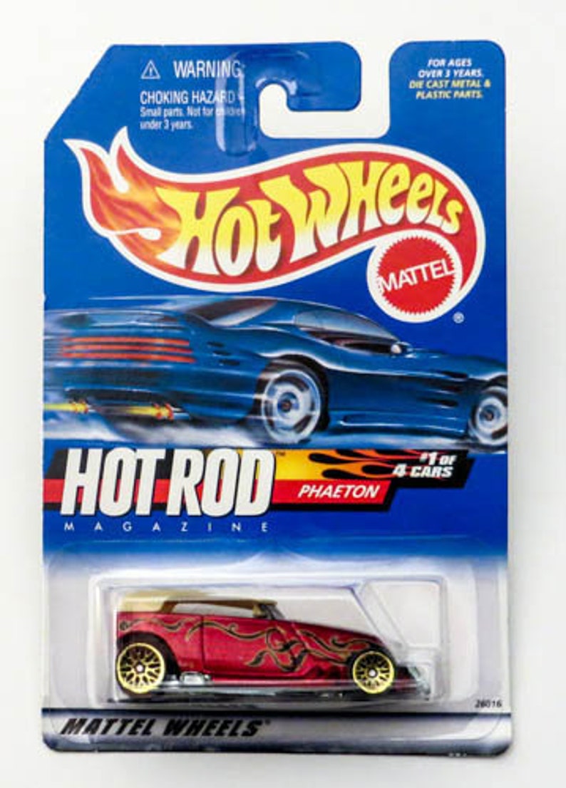 May include: A red Hot Wheels die-cast toy car with gold wheels and flames painted on the side. The car is labeled "Hot Rod Magazine Phaeton 1 of 4 Cars".
