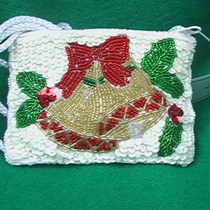 May include: A white sequined purse with a beaded design of two gold bells with red bows and green holly leaves. The purse has a white rope strap.