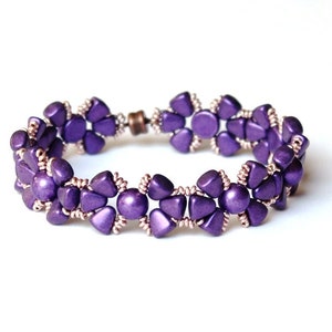 Op de afbeelding: Een paarse kralen armband met een magneetsluiting. De kralen zijn gerangschikt in een bloemmotief.