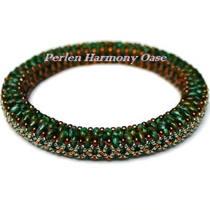 Könnte beinhalten: Ein grünes und kupferfarbenes Perlenarmband mit einem gewebten Muster. Das Armband besteht aus kleinen, runden Perlen und hat einen dezenten Schimmer. Der Text "Perlen Harmony Oase" ist auf dem Armband sichtbar.