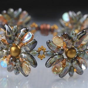 Könnte beinhalten: Ein Armband mit zwei blütenförmigen Designs. Die Blüten bestehen aus irisierenden blauen und grünen Perlen mit goldenen Akzenten.