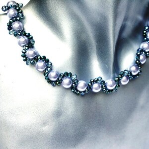 Könnte beinhalten: Eine zarte Halskette in Silber- und Blaugrüntönen. Die Halskette besteht aus einer Reihe kleiner, runder, silberner Perlen, die mit Clustern von blaugrünen Perlen durchsetzt sind.