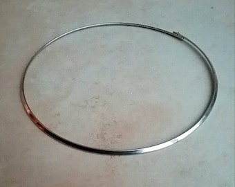 May include: A silver choker necklace with a simple, flat design.