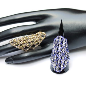 Könnte beinhalten: Zwei Perlenringe, einer in Gold und Rosa, der andere in Silber und Blau, auf einer schwarzen Handpuppe ausgestellt.