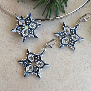 May include: A set of three snowflake earrings made with white and blue beads. The earrings are silver and have a dangling design.