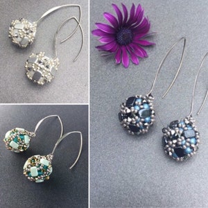 Könnte beinhalten: Drei Paar Hängeohrringe mit silbernen Haken. Die Ohrringe haben eine Perlenkugel in Silber, Schwarz und Weiß sowie Grün und Weiß.