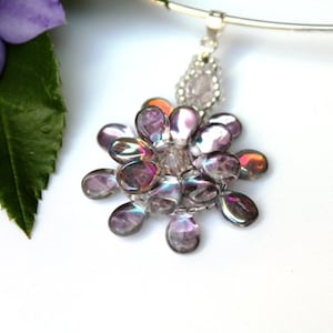 May include: A silver necklace with a pendant featuring a cluster of iridescent purple and pink beads in the shape of a flower.