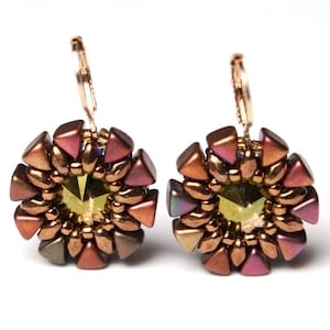 Könnte beinhalten: Ein Paar Ohrringe mit goldfarbener Oberfläche. Jeder Ohrring hat ein rundes, mehrfarbiges Perlenmuster mit einem grünen Kristall in der Mitte.