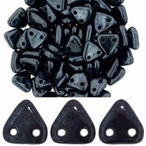 May include: A pile of dark grey triangle-shaped beads with two holes each. Three individual beads are shown below the pile.