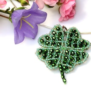 Könnte beinhalten: Eine silberne Kettenkette mit einem grünen vierblättrigen Kleeblatt-Anhänger aus Perlen.