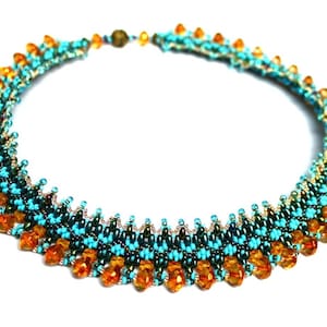 Puede incluir: Un collar de cuentas turquesa y ámbar con un diseño graduado. El collar está hecho con pequeñas cuentas de semillas y cuentas facetadas más grandes.