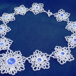 Könnte beinhalten: Eine silberne Perlenkette mit blauen Kristall-Akzenten in Form von Schneeflocken.