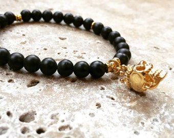 Totenkopf-Charm-Perlenarmband mit schwarzen Onyxperlen und goldenem Totenkopf. Rock-schicker alternativer Schmuck.