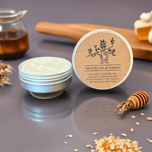 Könnte beinhalten: Zwei offene silberfarbene Metallbehälter mit Creme und dem Text "TWISTED SAJE RANCH" auf dem Deckel. Die Zutaten sind Hafermilch und ätherisches Honigöl mit Vitamin E und 100 % Gras gefüttertem Rindertalg. Ein kleiner hölzerner Honiglöffel und Haferflocken sind ebenfalls zu sehen.