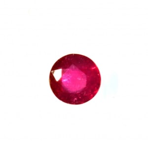 May include: A round, faceted ruby gemstone. The ruby is a deep, vibrant red color, with a polished surface that reflects light. The gemstone is set against a plain white background.