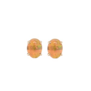 Könnte beinhalten: Ein Paar ovaler Ohrstecker mit im Cabochon-Schliff geschliffenen Opalen, die orangefarbene und grüne irisierende Blitze aufweisen und in vierzinkigen Fassungen aus goldfarbenem Metall sitzen. Die Steine haben eine glatte Oberfläche.