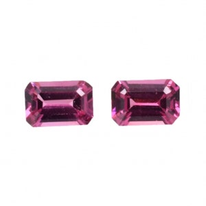 May include: Two pink rectangular gemstones with a faceted cut.
