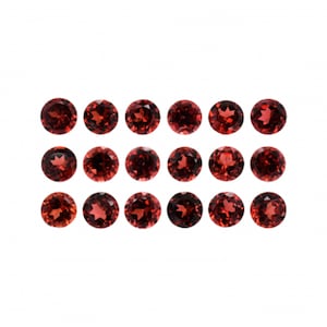 May include: A collection of 18 round, red gemstones. The gemstones are arranged in three rows of six.