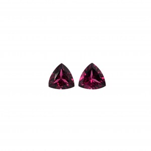 May include: Two triangular-shaped gemstones, each with a deep, rich purple hue. The stones are cut with facets that reflect light, creating a sparkling effect.