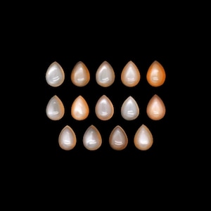Peut inclure: Une collection de 15 cabochons de pierres précieuses en forme de goutte d'eau dans différentes nuances de pêche et de blanc.