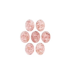 Könnte beinhalten: Sieben ovale Edelsteine, kreisförmig angeordnet. Die Steine sind durchscheinend mit rosa und weißen Einschlüssen, wodurch ein gesprenkelter Effekt entsteht. Die Edelsteine sind vor einem weißen Hintergrund angeordnet.